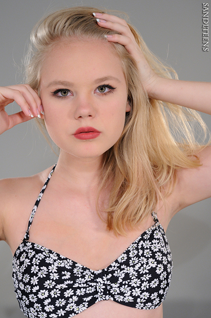 headshot of a pretty teen female blonde, blue-eyes wearing a floral print bikini top 